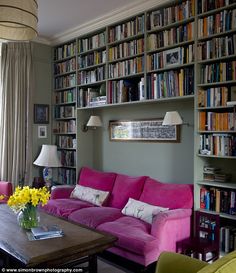 a living room filled with lots of furniture and bookshelves full of books on the walls