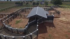 an aerial view of a barn with several stalls and horses in the fenced area