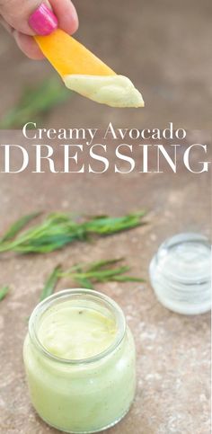 a person is dipping something into a small glass jar with the words creamy avocado dressing on it