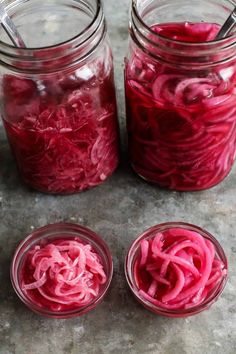 three jars filled with red onions sitting on top of a table