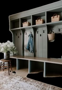 a bench with baskets and coats on it in the middle of a living room area