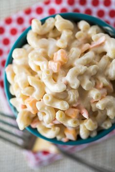 a bowl filled with macaroni and cheese on top of a red and white checkered cloth