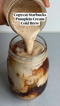 someone is pouring pumpkin cream into a mason jar filled with cold brew and caramel