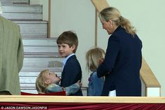 a group of people standing around each other in front of a staircase with two boys and one girl