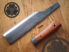 a knife with a wooden handle on top of a wood table next to a flower