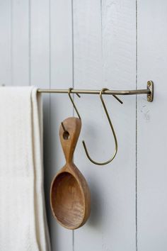 a wooden spoon hanging from a hook on a white wall next to a towel rack