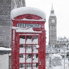 a red phone booth covered in snow with big ben in the background