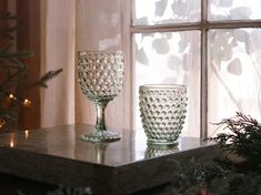 two glass goblets sitting on top of a table next to a christmas tree