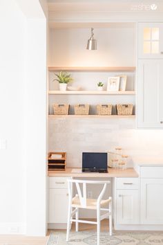 a white desk with a laptop computer on top of it next to a shelf filled with baskets