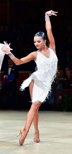 two people dressed in white dancing on a dance floor