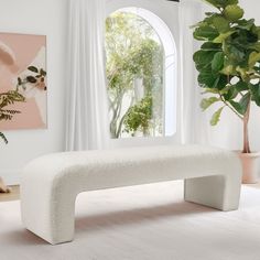 a white bench sitting in front of a window next to a potted green plant