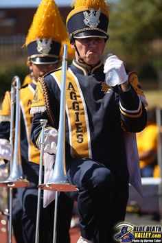 the marching band is dressed in blue and yellow uniforms with gold pompoms on their heads