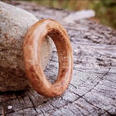 a wooden ring sitting on top of a piece of wood next to a tree trunk