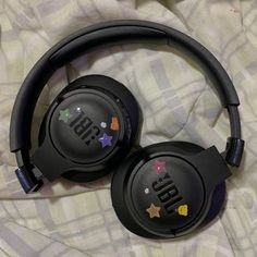 two black headphones sitting on top of a bed