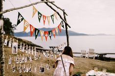 a woman sitting at a picnic table with pictures hanging from the trees and bunting