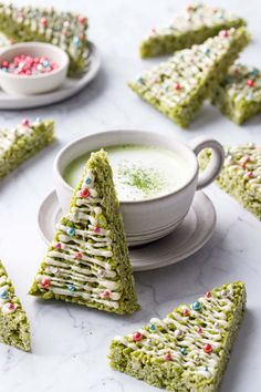 several pieces of green cake with sprinkles on them next to a cup and saucer