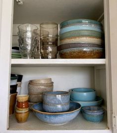 dishes and glasses are stacked on top of each other in a cabinet with glassware