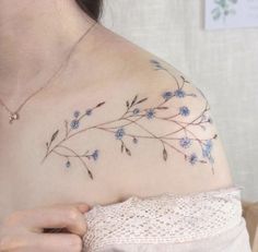 a woman's shoulder with blue flowers and leaves on her left side breast piece