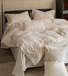 an unmade bed with white linens and pillows on top of it in a bedroom