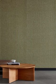 a wooden table sitting in front of a green wall with vertical blinds on it's side