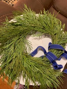 a green wreath sitting on top of a table next to a pair of blue ribbon