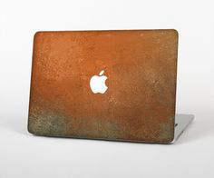 an apple laptop computer sitting on top of a white surface with rusted metal skin