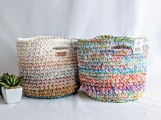 two woven baskets sitting next to each other on top of a white surface with a potted plant