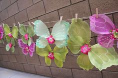 some paper butterflies are hanging on a clothes line with pink and green flowers attached to them