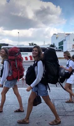 two girls walking down the street with backpacks on their back and one girl carrying a large bag