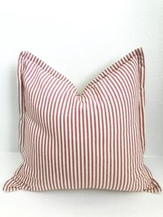 a red and white striped pillow sitting on top of a white table next to a wall