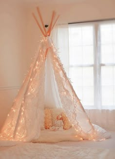 a teepee with some lights on it in a room next to a teddy bear