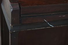 an old wooden desk with nails sticking out of the top and bottom drawer, in need of repair