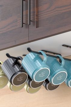 four coffee mugs are lined up on the counter in front of some cupboard doors