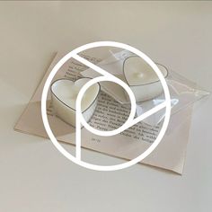 two heart shaped candles sitting on top of an open book with a white circle around it