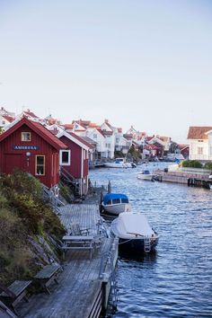 several boats are docked in the water next to some houses and buildings on stilts