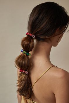 a woman with her hair in a pony tail braid, wearing two colorful flower clips