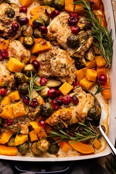 A roasting pan with chicken thighs, cut up butternut squash, cranberries, and brussels sprouts with fresh rosemary on top. Chicken And Squash Recipes, Chicken And Acorn Squash Sheet Pan Dinner, Butternut Squash Chicken Sausage, Butternut Squash And Cranberries, E2m Recipes, Sheet Pan Maple-dijon Chicken With Butternut Squash And Brussels Sprouts, Squash Tart