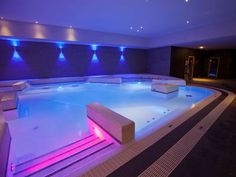 an indoor swimming pool is lit up with blue lights