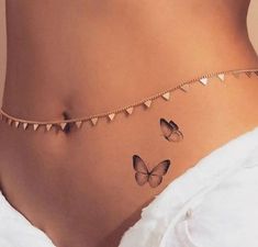 a woman's stomach with two butterflies on it and a chain around her waist