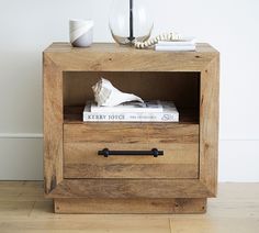 a wooden cabinet with two drawers and a book on top that has some books in it