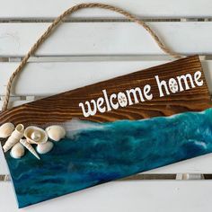 a welcome home sign hanging on a wall with sea shells and seashells in the foreground