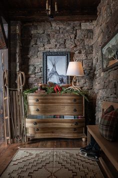 a wooden dresser sitting in the corner of a room next to a lamp and pictures