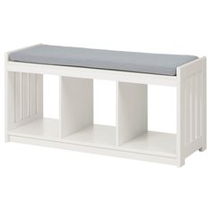 a white bench with a cushion on it's seat and two shelves below the bench