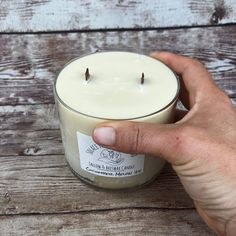 a hand holding a candle on top of a wooden table