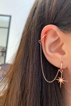 a close up of a person's ear with a star and chain on it