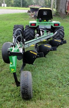 a green tractor is parked in the grass with two large wheels on it's back