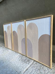 three framed art pieces sitting on the side of a building