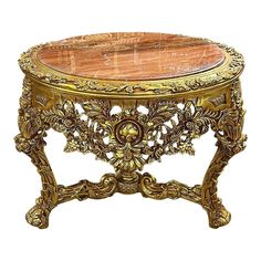 an ornately carved wooden table with gold leaf accents on it's sides and a marble top