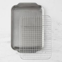 two stainless steel baking pans sitting on top of a white marble countertop next to each other