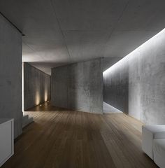 an empty room with wood flooring and concrete walls